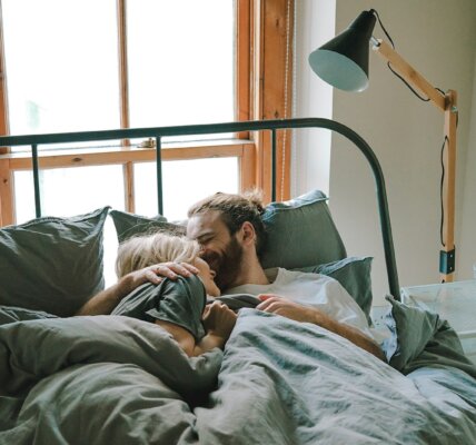 man kissing woman on her forehead
